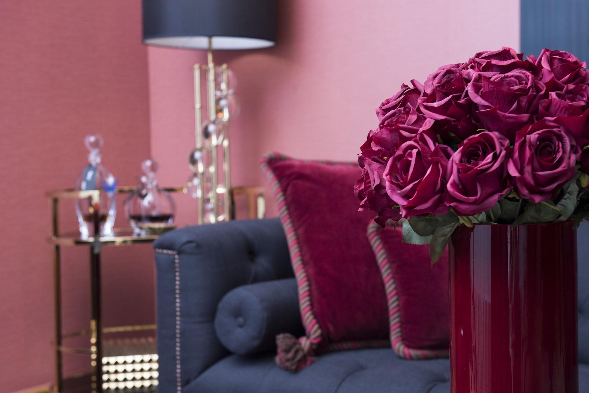 Hotel Palace Berlin Kültér fotó A living room with a dark blue sofa and a red vase